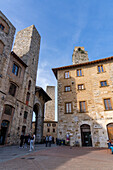 Mittelalterliche Türme um die Piazza della Cisterna in der ummauerten Stadt San Gimignano, Italien. L-R: Torri degli Ardinghelli, Torre Salvucci und die Spitze des Torre Rognosa.