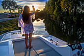 Girl in the sunset on the deck of a boat. Canal du Midi near Carcassonne Aude South of France southern waterway waterways holidaymakers queue for a boat trip on the river, France, Europe