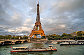 Scenic panorama of Eiffel Tower, Seine River, and pont d'lena in Paris, France; with a cruise passing by ferry