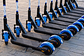 A row of rechargeable electric scooters for rent in front of the train station in La Spezia, Italy.