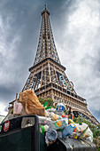 An overflowing rubbish bin on a pavement in front of the Eiffel Tower in Paris