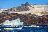 Kangerlussuaq Fjord. Large iceberg in scenic fjord surrounded by snow-capped mountains, Southeast coast, Greenland