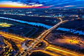 A49 highway connects Sevilla to Huelva, crossing the Guadalquivir River at sunset. Traffic flows smoothly under a colorful sky.