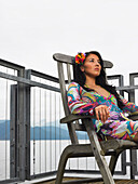 Frau auf Deck sitzend mit Meerblick