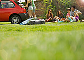 Teenager sitzen auf Gras und beladen ein Auto