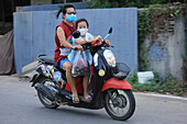 Eine Frau und ihre Tochter fahren auf einem Motorrad auf dem Rückweg vom Markt in der Nähe von Mae Sot, Thailand