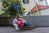 Portugal, Insel Madeira. Funchal, Straße Caminho do Monte. Abstieg vom tropischen Garten in einem Weidenkorb.