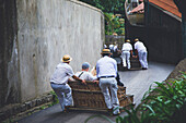 Portugal, Insel Madeira. Funchal, Straße Caminho do Monte. Abstieg vom tropischen Garten in einem Weidenkorb.