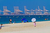 Naher Osten, Vereinigte Arabische Emirate, Dubai. Öffentlicher Strand von Jebel Ali. Im Hintergrund die Kräne des Hafens von Jebel Ali