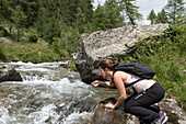 Wanderin erfrischt sich am Wildbach, Rivatal (Reintal), bei Ahrntal (Ahrntal), Südtirol (Alto Adige), Italien