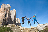 Hikers jumping at foot of Tre Cime di Lavaredo (Three Peaks of Lavaredo), Three Peaks Nature Park, Dolomites, UNESCO, South Tyrol, Italy