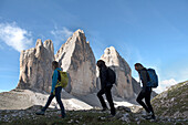 Three hikers at foot of Tre Cime di Lavaredo (Three Peaks of Lavaredo), Three Peaks Nature Park, Dolomites, UNESCO, South Tyrol, Italy