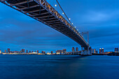 Blick auf die Regenbogenbrücke und Koto City im Hintergrund in der Abenddämmerung, Minato City, Tokio, Honshu, Japan