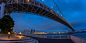 Blick auf die Regenbogenbrücke und Koto City im Hintergrund in der Abenddämmerung, Minato City, Tokio, Honshu, Japan