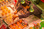 Elevated view of colourful fresh fruit stall and stall holder in Omicho Market, Kanazawa City, Ishikawa Prefecture, Honshu, Japan