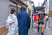 Blick auf ein Paar in Kimonos und Rikscha in Gion, Kyotoer Geisha-Viertel, Kyoto, Honshu, Japan