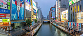 View of colourful adverts in Dotonbori, vibrant entertainment district near the river at dusk, Osaka, Honshu, Japan