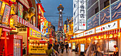 View of Tsutenkaku Tower and restaurants neon lights at dusk in the Shinsekai area, Osaka, Honshu, Japan