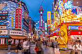 View of Tsutenkaku Tower and restaurants neon lights at dusk in the Shinsekai area, Osaka, Honshu, Japan