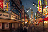 View of Tsutenkaku Tower and restaurants neon lights at night in the Shinsekai area, Osaka, Honshu, Japan