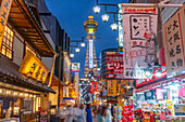 View of Tsutenkaku Tower and restaurants neon lights at dusk in the Shinsekai area, Osaka, Honshu, Japan