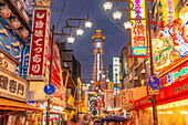 View of Tsutenkaku Tower and restaurants neon lights at dusk in the Shinsekai area, Osaka, Honshu, Japan