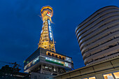 View of Tsutenkaku Tower and restaurants neon lights at dusk in the Shinsekai area, Osaka, Honshu, Japan