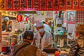 View of hot food restaurant near Tsutenkaku Tower at dusk in the Shinsekai area, Osaka, Honshu, Japan