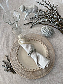 Österliche Tischdekoration mit Weidenkätzchen, Lämmchen aus Keramik und mit Weidenkätzchen beklebtes Ei