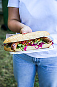 Char sausage hot dog with leaf salad and red cabbage