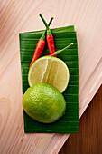 Limes and chilli peppers on a banana leaf