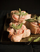 Raw pork chops barded with pancetta and sage