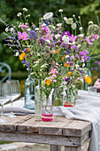 Gedeckter Tisch mit Blumenschmuck, Ringelblume (Calendula), Kosmee (Cosmos), Flammenblume (Phlox), Skabiose, Kugellauch (Allium) in Vasen