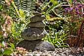 Steinmännchen und Farnblätter im sommerlichen Garten 