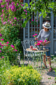 Frau mit Rosenstrauss, Rosenstauden (Rosa multiflora 'Taunusblümchen'), Kletterrose am Teehaus neben Sitzplatz