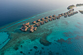 Luftaufnahme eines Luxusresorts mit Bungalows entlang der Riffbarriere auf dem Raa-Atoll, Malediven-Archipel