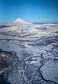 Luftaufnahme einer Gebirgslandschaft mit einem Fluss, der das Tal durchquert, im Winter mit Schnee in der Region Kamtschatka Krai, Russland