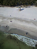Aerial view of a beautiful beach with a lifeguard house,palm trees,and people enjoying the sunny shoreline,Bradenton Beach,Florida,United States