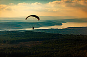 Aerial view of single paramotor pilot flying over forest near a reservoir lake on the northeastern coast of Istanbul,Turkey