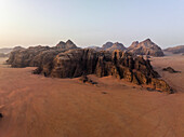 Luftaufnahme eines majestätischen Gebirges und einer weiten Sandwüste bei einem ruhigen Sonnenuntergang, Akaba, Jordanien