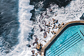 Aerial View Of Large Ocean Waves Breaking Towards Natural Water Coastal Swimming Pool With Person Swimming In Bronte,Sydney,Australia
