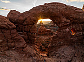 Aerial view of a majestic natural arch and dramatic rock formations at sunset,Moab,United States