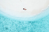 Aerial Top Down View Of Female Model Lying On White Sand Beach In South Male Atoll,Maldives