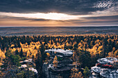 Aerial view of big stone in the autumn forest in time of the sunset with sitting people on the top,Usva,Perm Krai,Russia