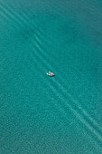 Aerial view of a two tiny people canoeing into the sea in Cefalù,Sicily,Italy