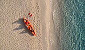 Aerial view of three beautiful girls sitting on an orange kayak while chatting and relaxing in front of a crystalline sea in Montepaone,Calabria,Italy
