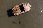 Keraniganj,Bangladesh - 20 June 2020: Aerial view of a few kids playing and swimming in Buriganga river,jumping from a wreck old boat,Dhaka,Bangladesh