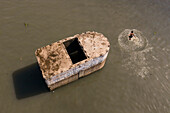 Keraniganj,Bangladesh - 20 June 2020: Aerial view of a few kids playing and swimming in Buriganga river,jumping from a wreck old boat,Dhaka,Bangladesh