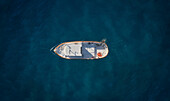Aerial view of a little fishing boat at dawn surrounded by a crystalline deep blue sea moored in the Ionian Sea,Calabria,Italy