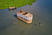 Keraniganj,Bangladesh - 20 June 2020: Aerial view of a few kids playing and swimming in Buriganga river,jumping from a wreck old boat,Dhaka,Bangladesh
